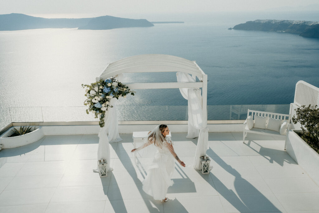 A menyasszony áll az erkélyen Santorini tengerre néző panorámájával